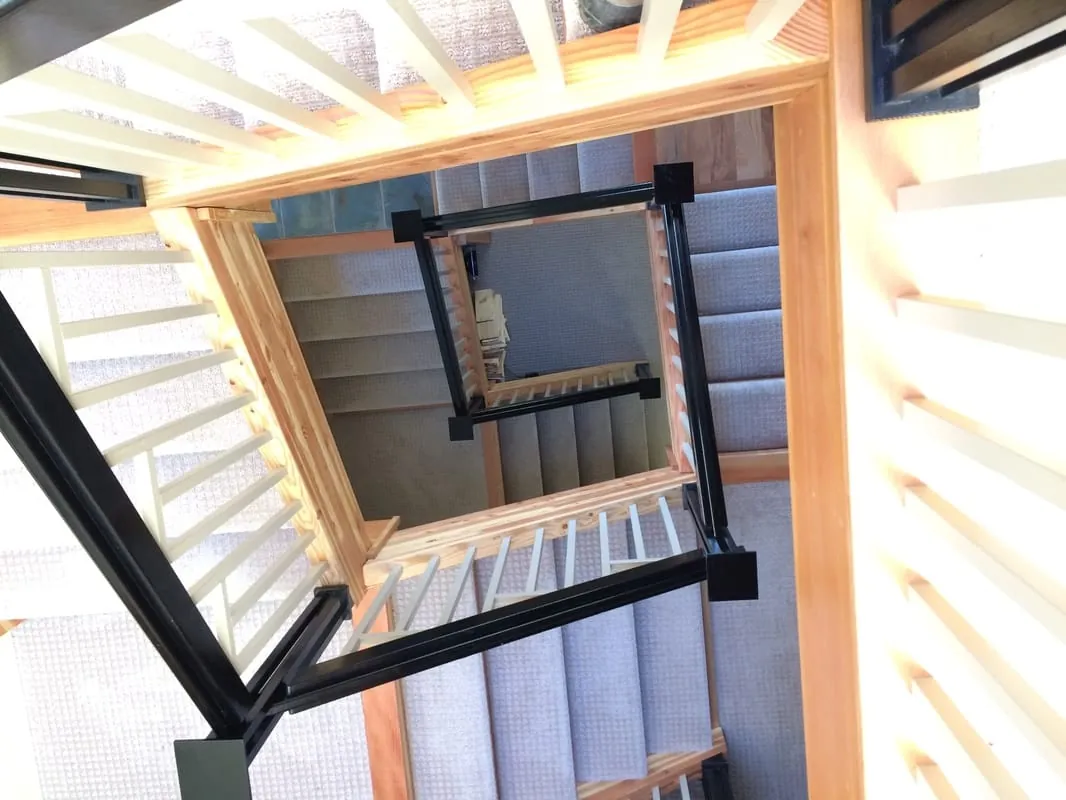 Looking up a multi-story custom staircase with black railings