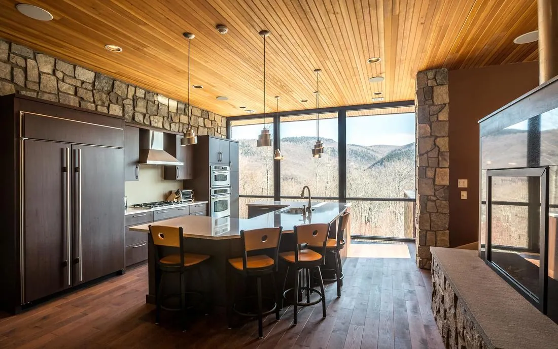 Custom kitchen with wood ceiling, stone wall and a glass wall framing mountain views