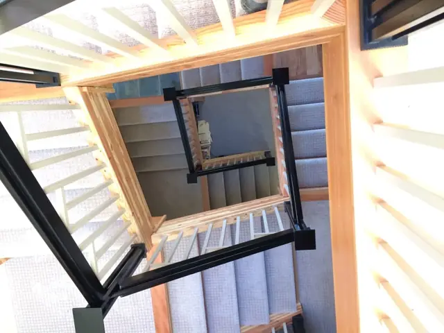 Looking up a multi-story custom staircase with black railings