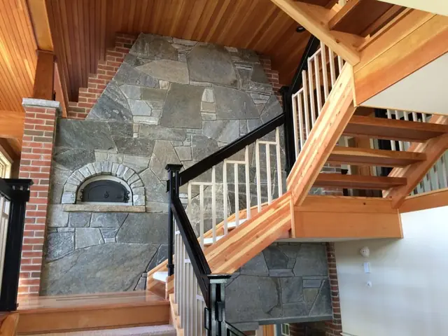 Custom wood staircase beside a fieldstone wall