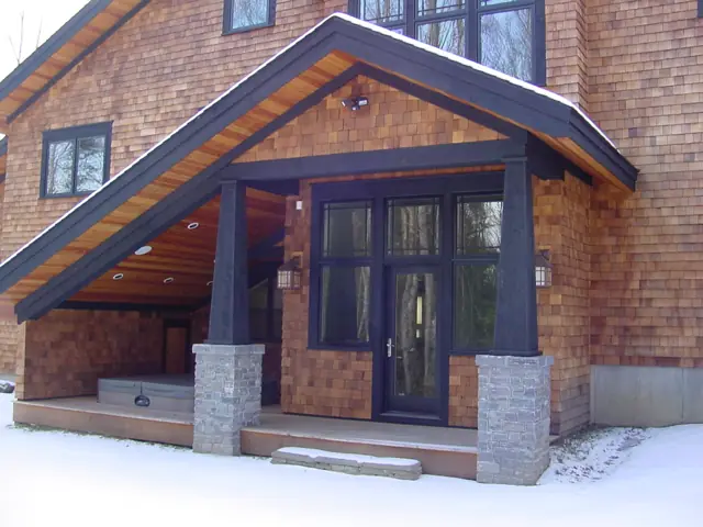Stone and shingle entry with a gabled glass porch