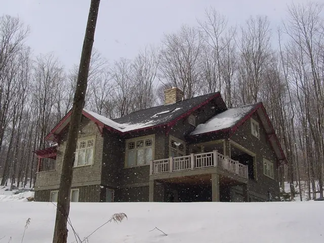 Craftsman home with stone chimney after a snowfall