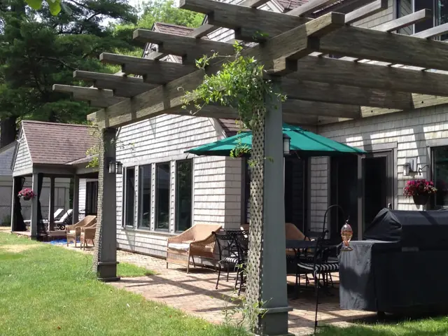 Pergola-covered patio beside a shingle home
