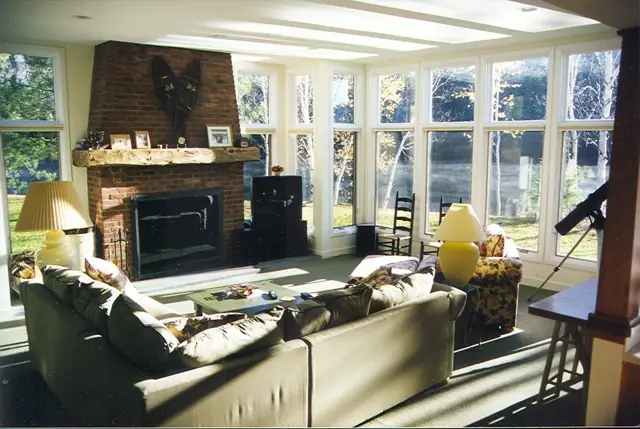 Sunlit living room with fireplace and a wall of windows