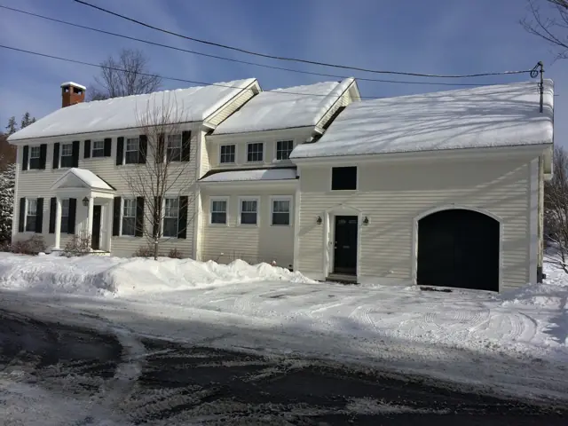 White colonial-style homes with snowy drive