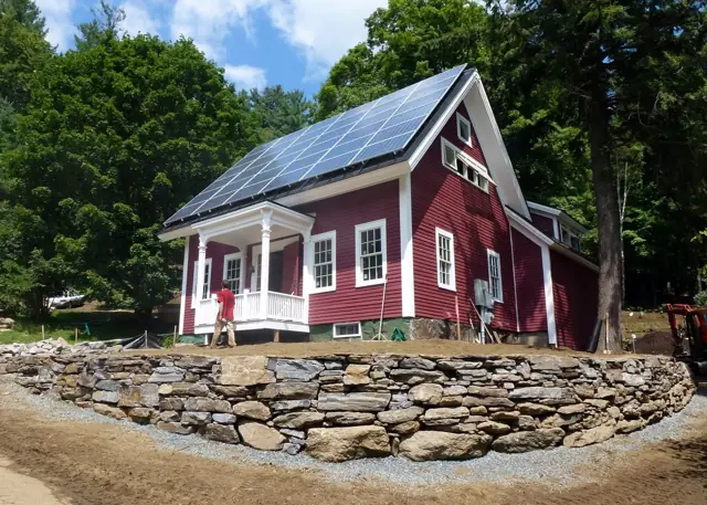 Red metal-roof farmhouse on a dry-laid stone wall
