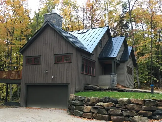 Gray home with metal roof and two-car garage in autumn